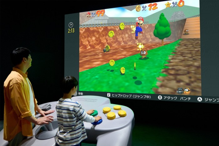 Un jugador empuja los controles de un juego en un controlador de gran tamaño frente a una pantalla gigante