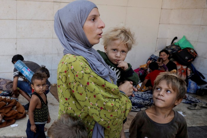 Desplazada de Dahiyeh, suburbio del sur de Beirut, Asmaa Kenji sostiene a uno de sus tres hijos mientras viven en las calles del centro de Beirut después de huir de los ataques aéreos israelíes, en Beirut, Líbano.