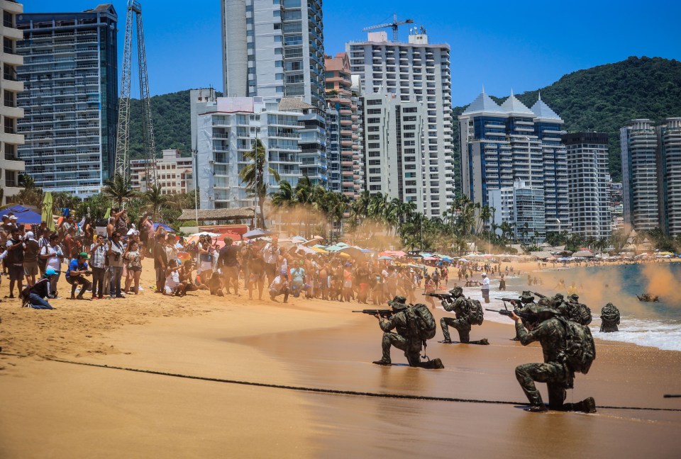 Miembros de la Armada de México participan en una práctica de rescate anfibio mientras los turistas observan horrorizados