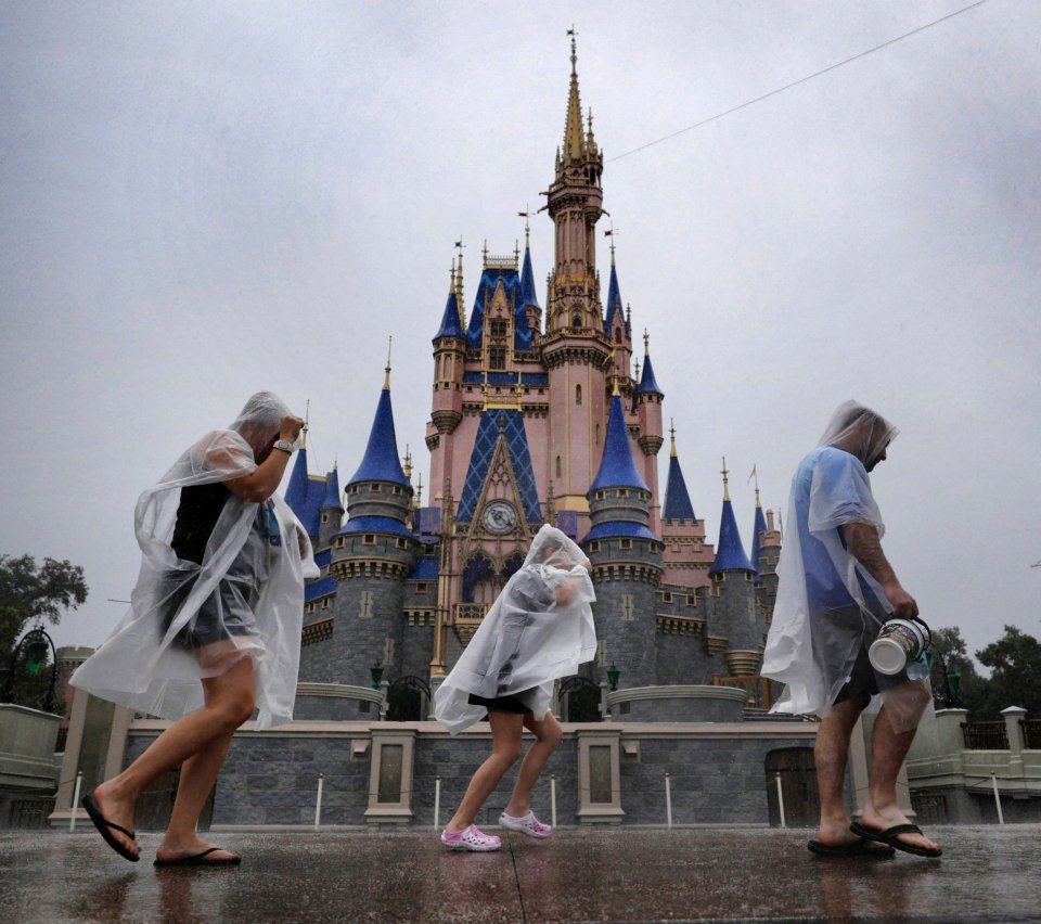 Los visitantes resisten las primeras lluvias del huracán Milton en Magic Kingdom en Walt Disney World el miércoles