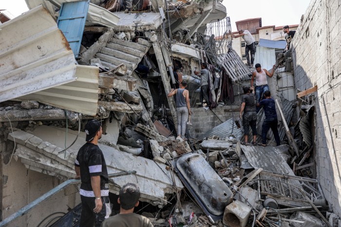 Personas afuera de un edificio derrumbado en Jabalia, al norte de Gaza, mientras intentan sacar a un hombre atrapado bajo los escombros tras un bombardeo israelí el martes.