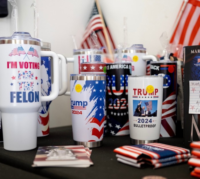 La imagen muestra una variedad de productos políticos, principalmente tazas y vasos de viaje, que apoyan a Donald Trump para las elecciones presidenciales de EE. UU. de 2024.