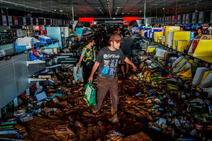 La gente recoge mercancías en un supermercado afectado por las inundaciones en Valencia