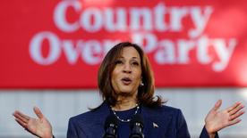 Kamala Harris está detrás de un atril y frente a un cartel rojo que dice "País sobre fiesta".