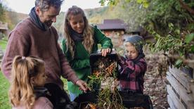 Una familia arroja residuos de cocina a una pila de abono en el jardín.