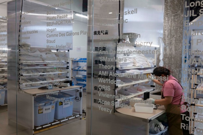 Un trabajador con una camisa rosa y un delantal organiza artículos en los estantes dentro de la tienda ZZER de Shanghai.