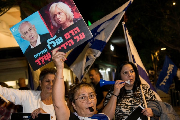 Un manifestante levanta un cartel con imágenes del primer ministro israelí, Benjamin Netanyahu, y del fiscal general israelí, Gali Baharav-Miara, durante una manifestación frente a la casa del fiscal general israelí.