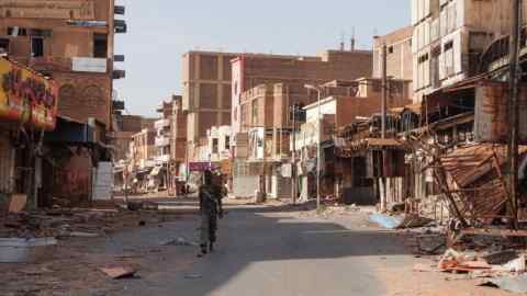 Un miembro de las fuerzas armadas de Sudán camina entre edificios dañados en Omdurman