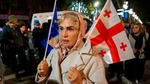 Una mujer sostiene banderas de la UE y de Georgia durante una protesta de la oposición contra los resultados de las elecciones parlamentarias en Tbilisi, Georgia.