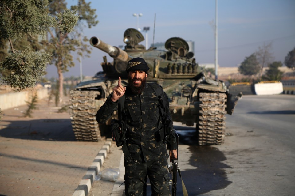 Un hombre armado frente a un tanque después de que las fuerzas rebeldes tomaran el control de la ciudad.