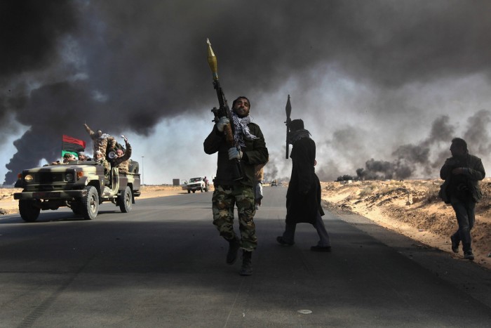 Los rebeldes libios luchan contra las tropas gubernamentales mientras el humo de una instalación petrolera dañada oscurece el cielo el 11 de marzo de 2011 en Ras Lanuf, Libia.