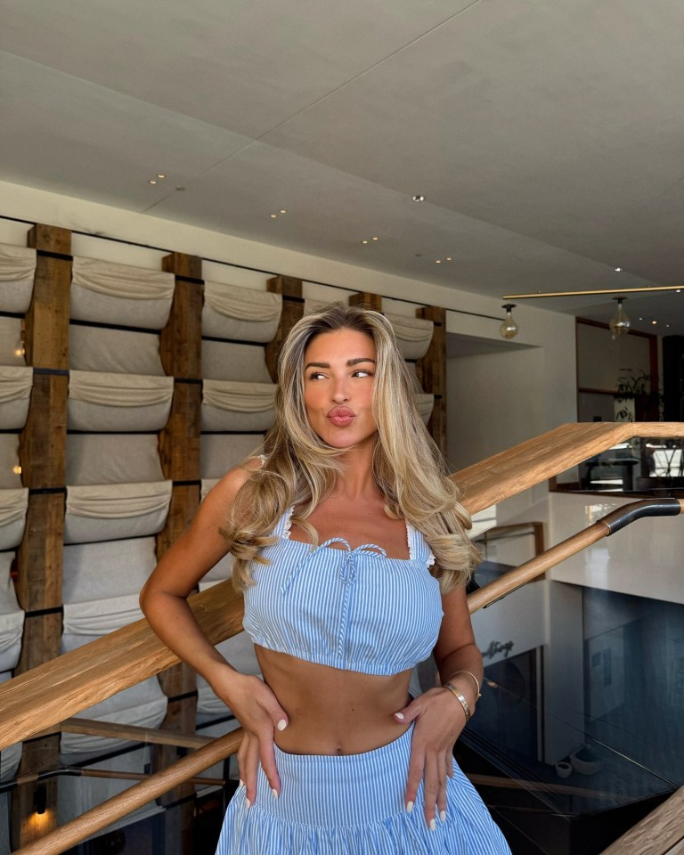 Zara McDermott posando en una blusa de rayas azules y una falda.