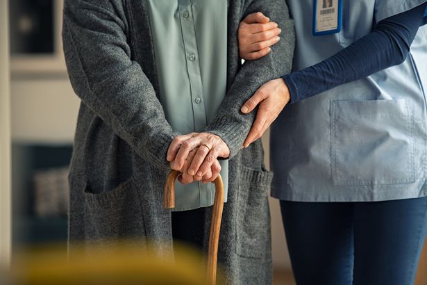 Primer plano de las manos del cuidador médico ayudando a la anciana en la clínica privada