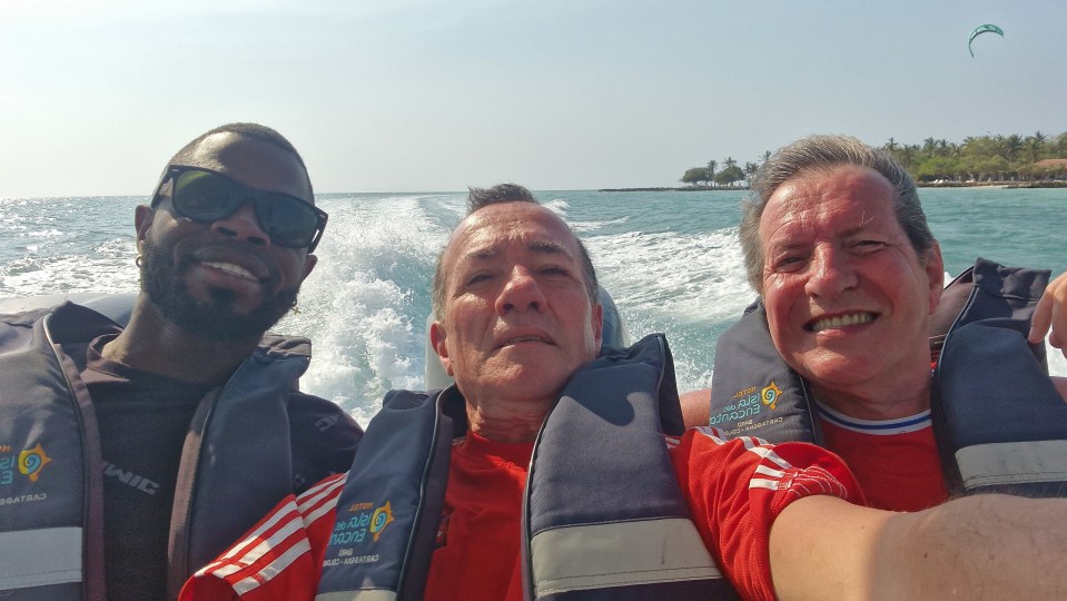 Tres hombres en los chalecos salvavidas en un bote.
