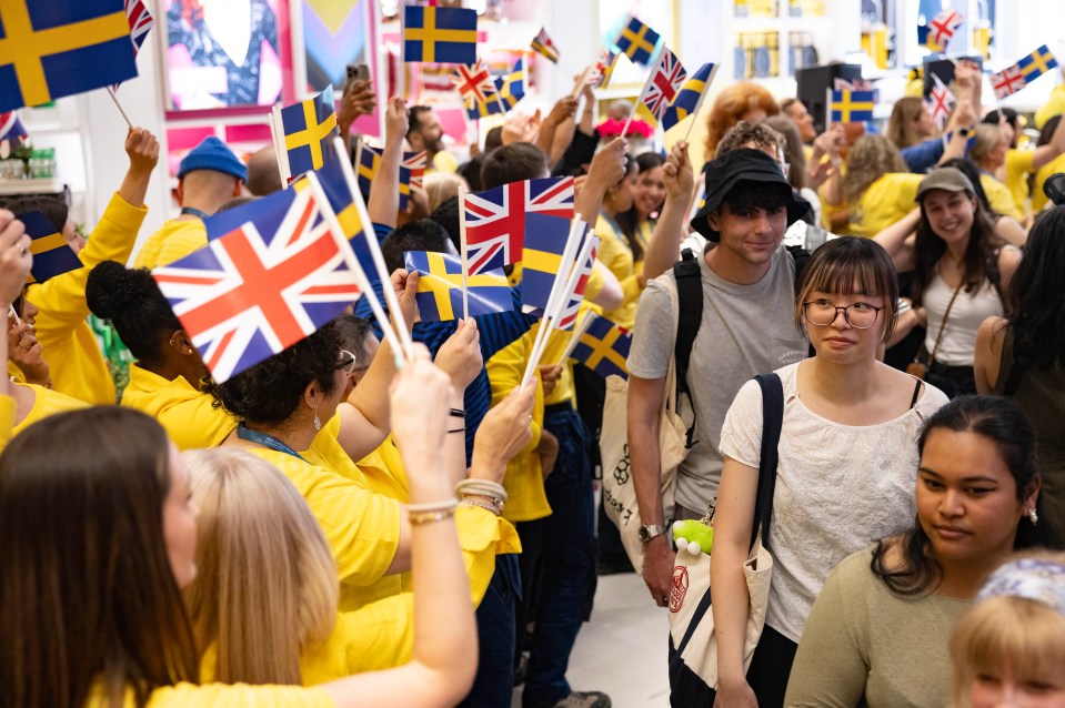 Personas que sostienen banderas británicas y suecas en una tienda IKEA.
