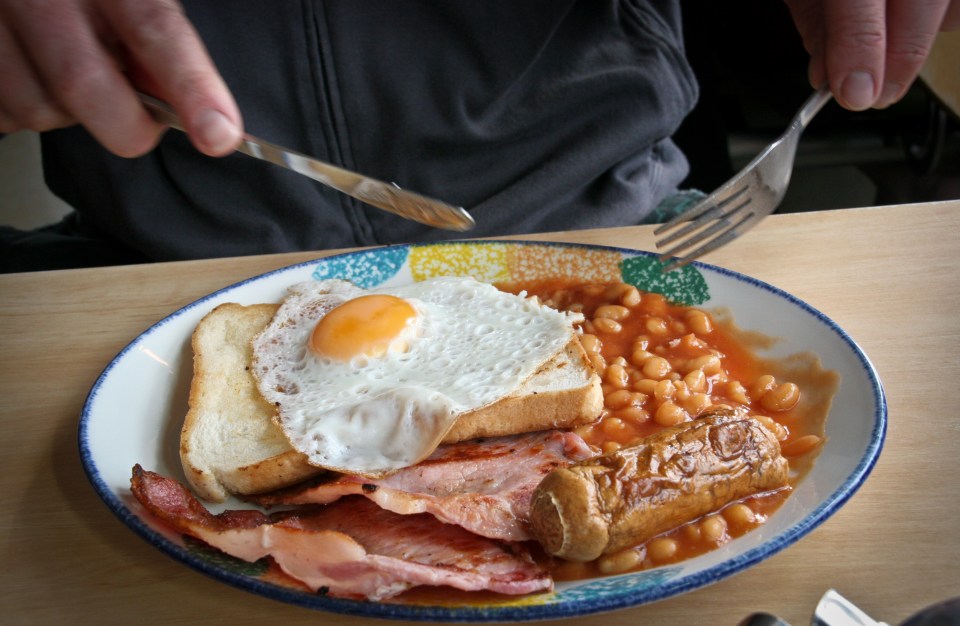 Persona comiendo un desayuno inglés completo.