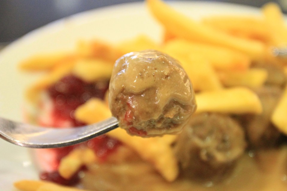 Albóndigas en un tenedor con salsa de salsa, papas fritas y lengonerras en el fondo.
