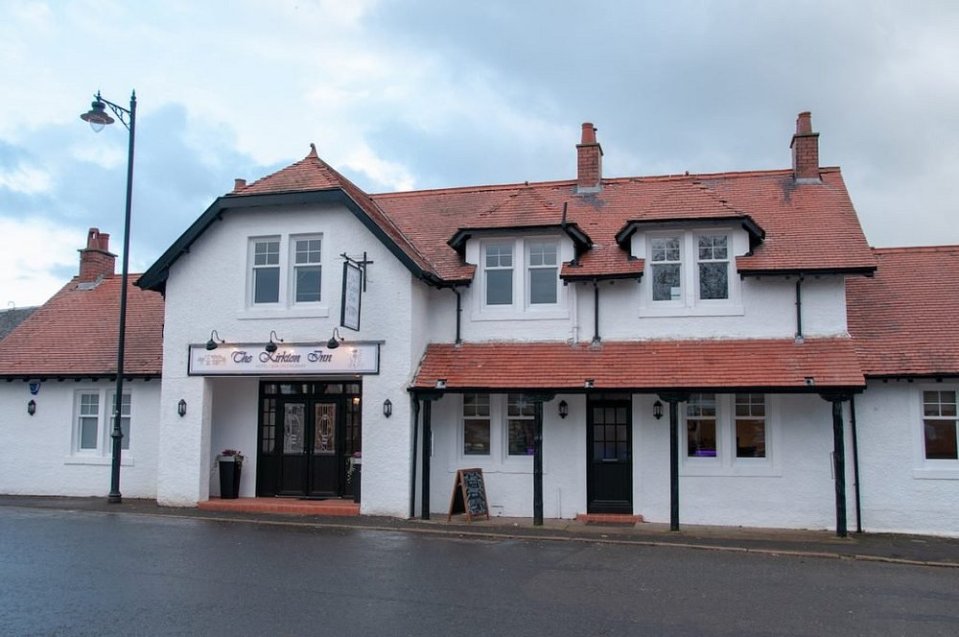 El Kirkton Inn, un edificio blanco con un techo de azulejos rojos.