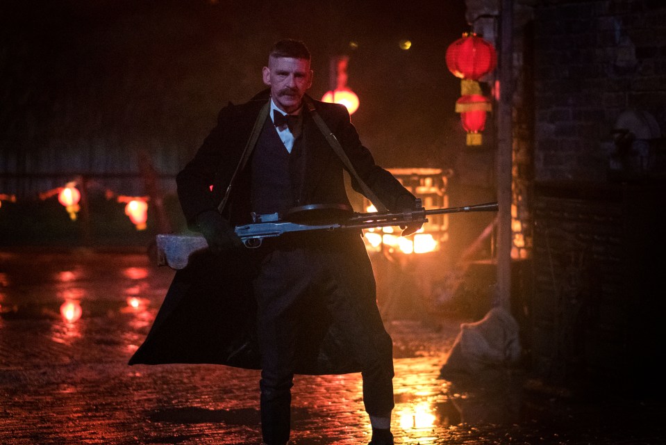 Arthur Shelby de Peaky Calasas que llevan una ametralladora.