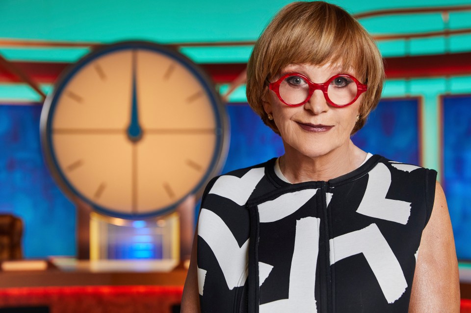 Anne Robinson con una tapa estampada en blanco y negro y gafas rojas.