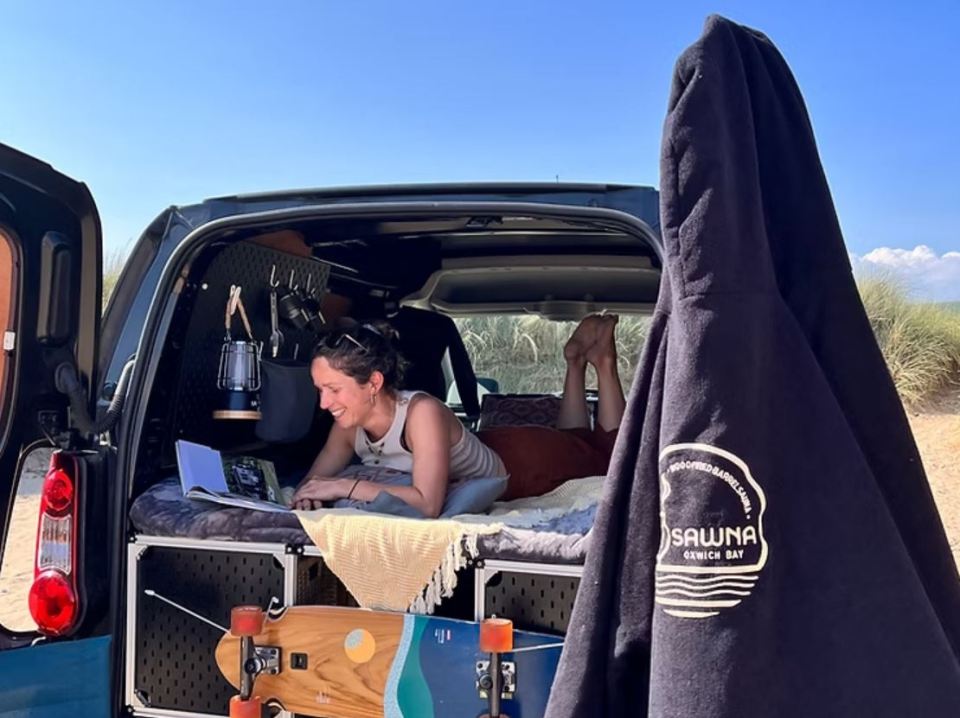 Mujer relajándose en una camioneta, leyendo un libro.