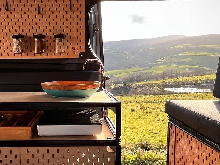 Cocina de campista de conversión de furgonetas con fregadero y vista panorámica.