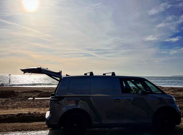 La camioneta estacionó en una playa con su puerta trasera abierta.