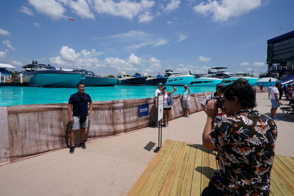 Los fanáticos de la carrera toman fotos en un puerto deportivo hecho por el hombre.