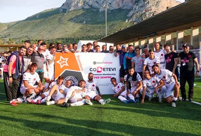 Equipo de fútbol posando con el letrero de un patrocinador.