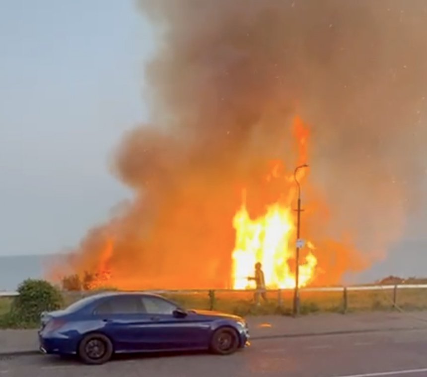 Gran incendio forestal que envuelve un acantilado cerca de una playa.