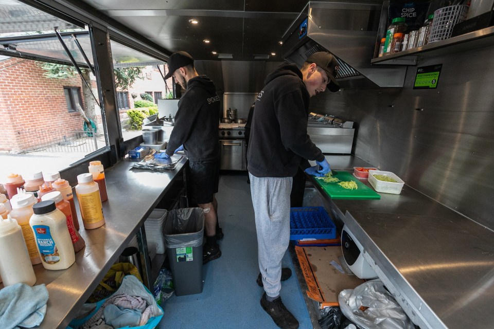 Dos personas que preparan comida dentro de un camión de comida.