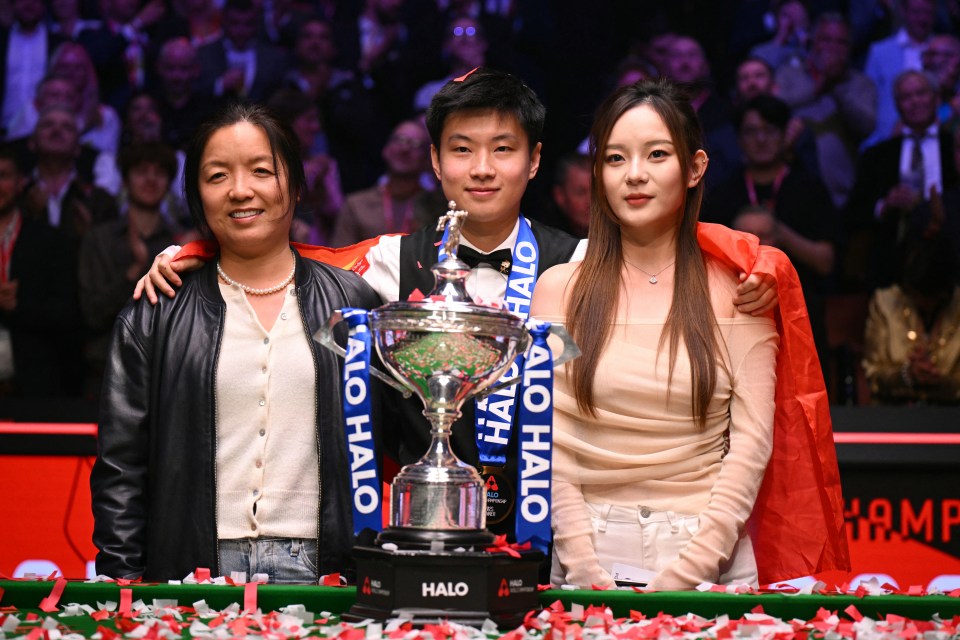 Zhao Xingong con su novia y el jefe de la Academia Sheffield Snooker posando con el Trofeo del Campeonato Mundial de Snooker.