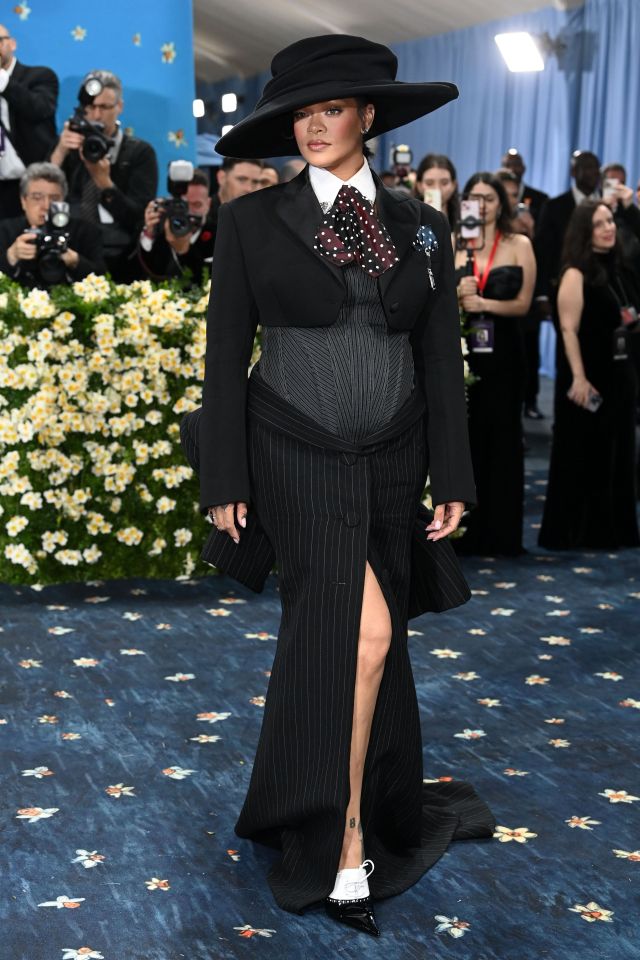 Rihanna en la Gala Met 2025 con un traje de rayas negras y un sombrero de ala ancha.