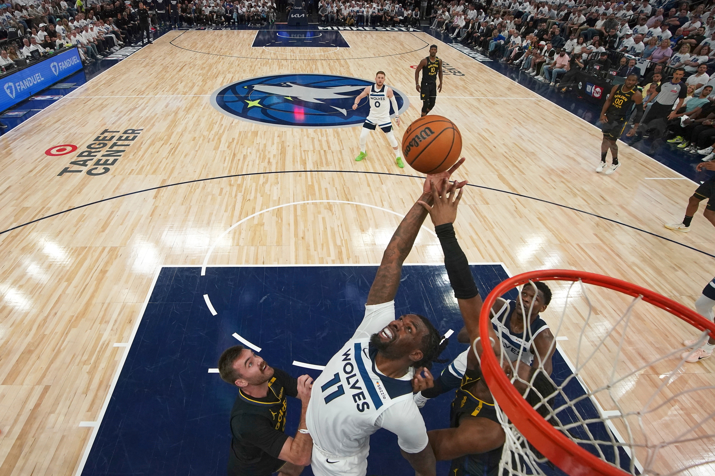El Centro de Minnesota Timberwolves Naz Reid (11) busca un rebote contra el guardia de los Golden State Warriors, Pat Spencer, a la izquierda, y al delantero Kevon Looney, a la derecha, durante la segunda mitad del Juego 1 de una serie de playoffs de segunda ronda de baloncesto de la NBA, el martes 6 de mayo, 2025, en Minneapolis. (Photo AP/Abbie Parr)