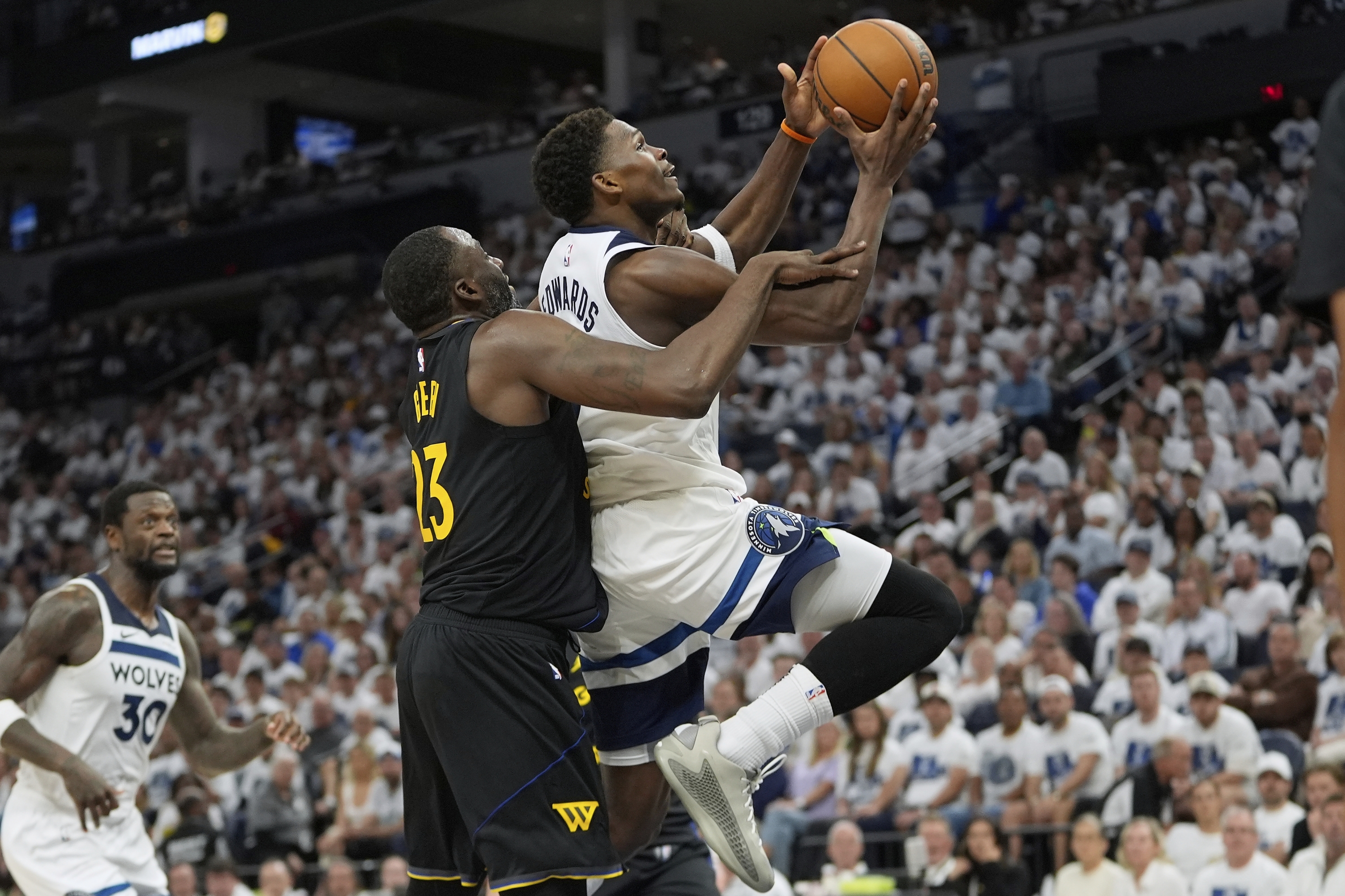 El guardia de los Minnesota Timberwolves, Anthony Edwards (5), a la derecha, está abordado por el delantero de Golden State Warriors, Draymond Green (23) durante la segunda mitad del Juego 1 de una serie de playoffs de segunda ronda de baloncesto de la NBA, el martes 6 de mayo de 2025, en Minneapolis. (Photo AP/Abbie Parr)
