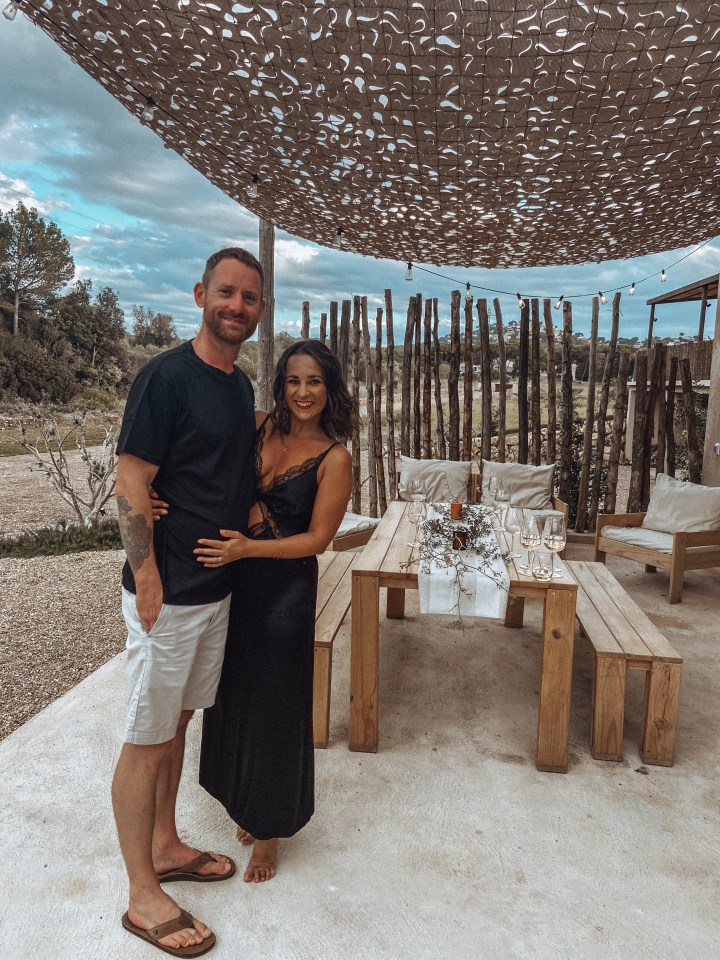 Pareja de pie juntos al aire libre cerca de una mesa para comer.