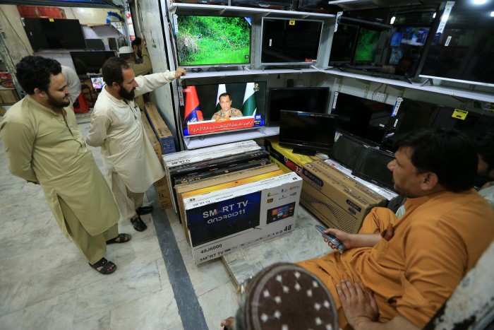 La gente ve informes de televisión de huelgas de misiles indios en Pakistán