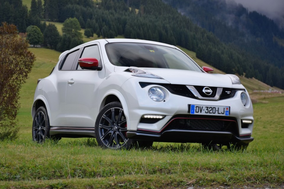 Nissan Juke blanco estacionado en un campo cubierto de hierba.