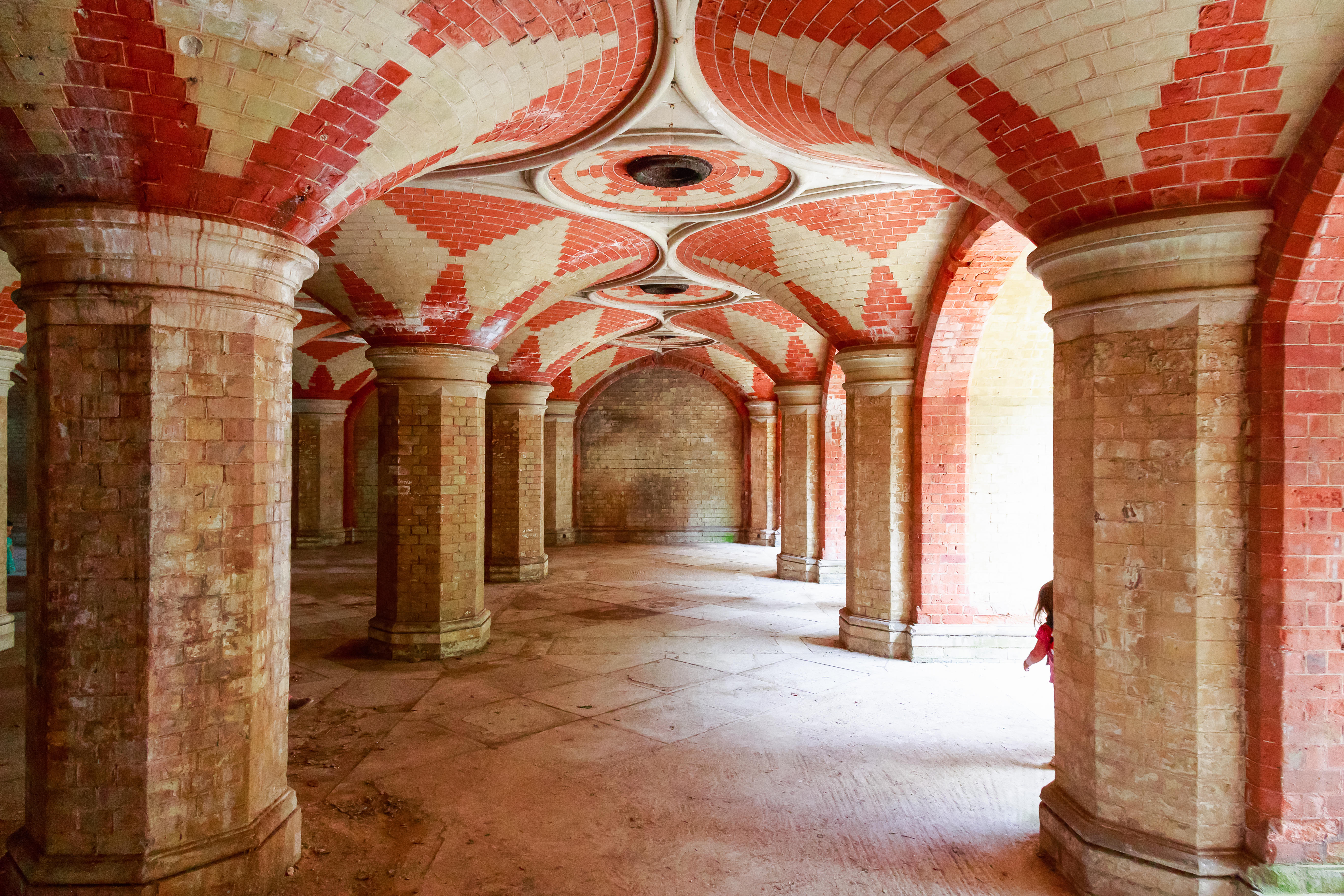 Interior de un túnel peatonal victoriano en desuso con ladrillo rojo y blanco.