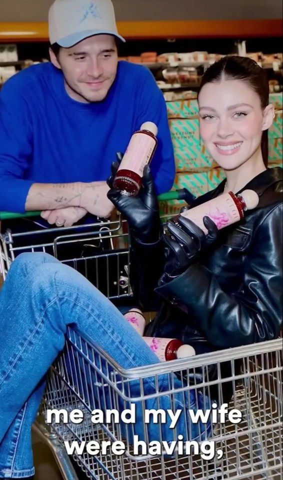 Brooklyn Beckham y su esposa en un carrito de compras, sosteniendo botellas de salsa picante.