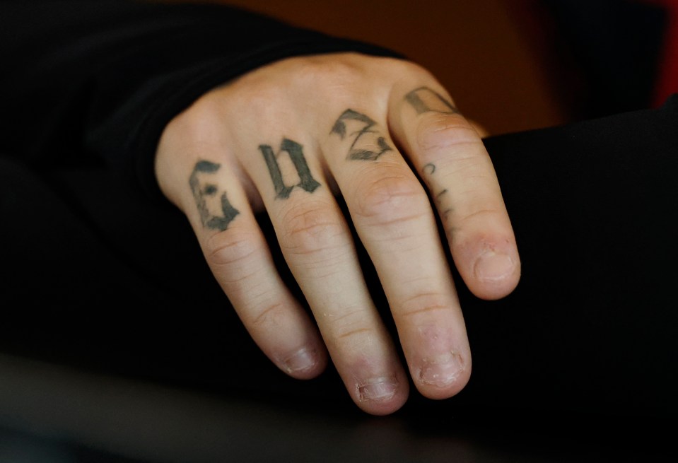 Primer plano de una mano con tatuajes en los dedos.