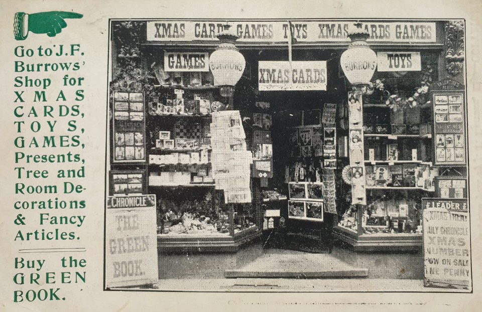 Foto en blanco y negro de la ventana de la tienda de Burrows que muestra tarjetas de Navidad, juguetes y juegos.