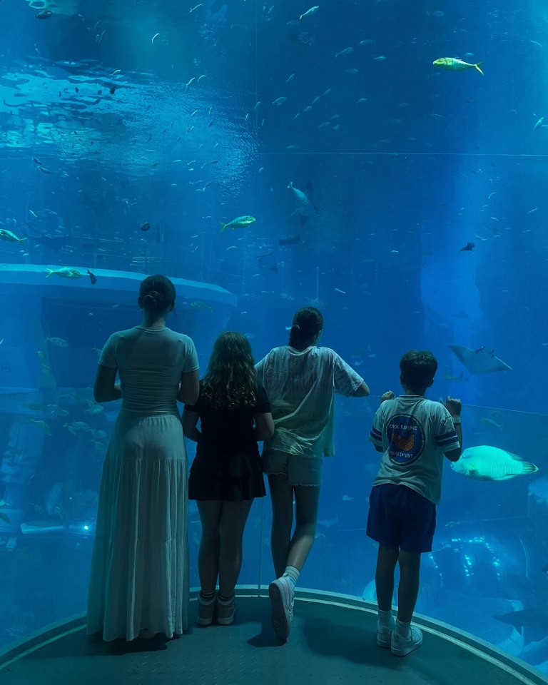 Familia viendo un gran tanque de acuario lleno de peces.