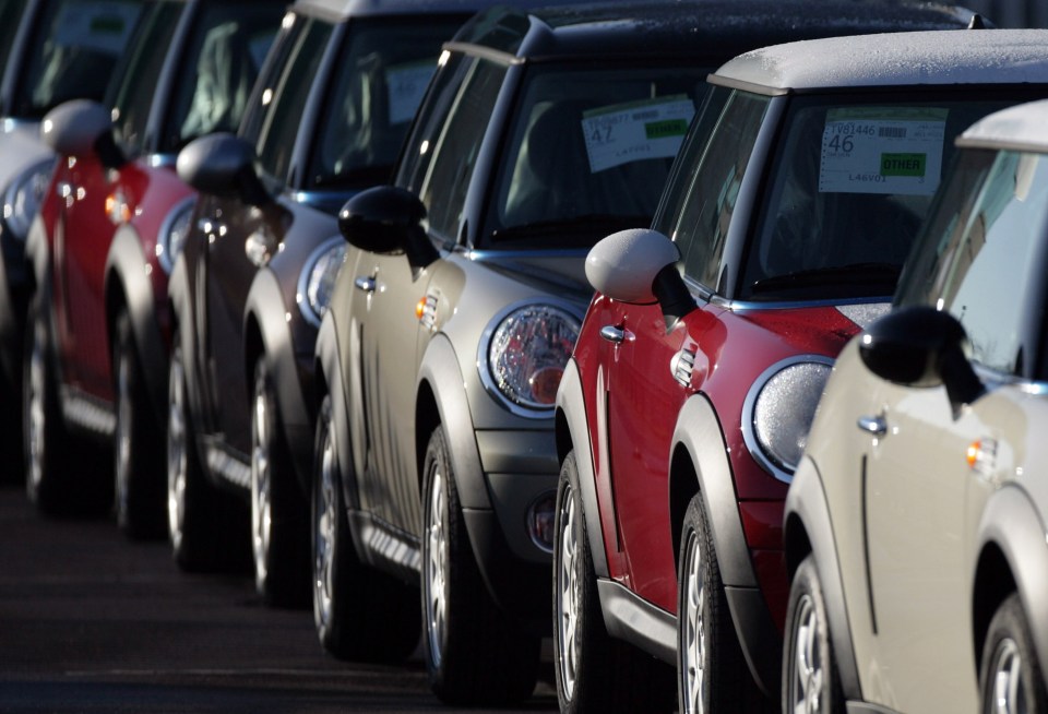 Mini coopers estacionados en una fila en una fábrica.