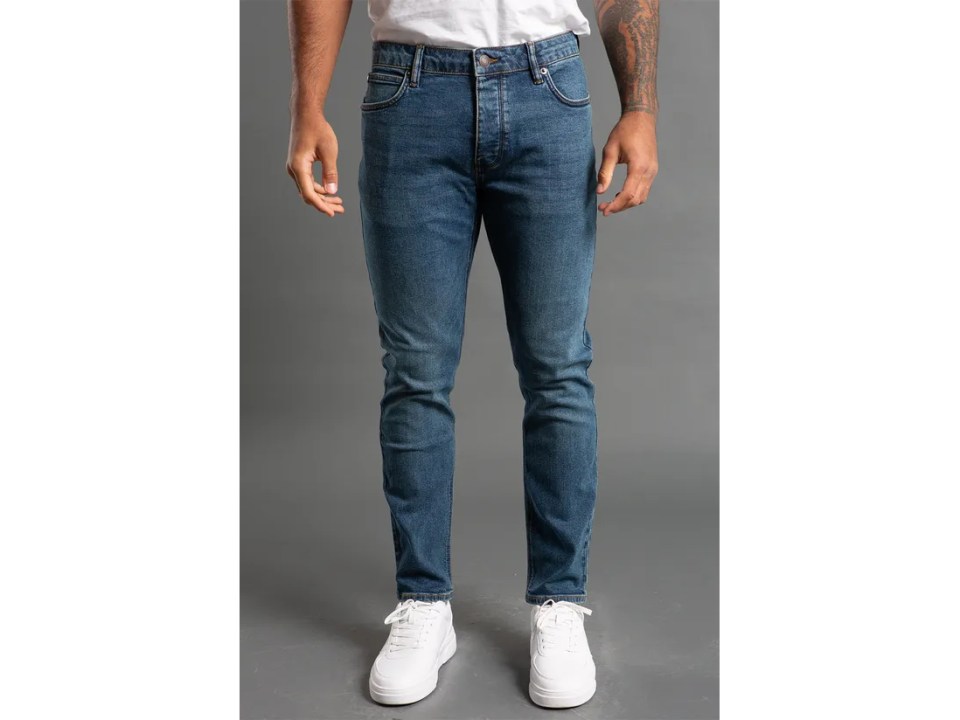Hombre con jeans estiramientos delgados y zapatillas blancas.
