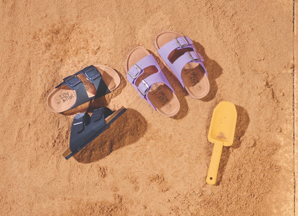 Sandalias para niños en arena con una pequeña pala.