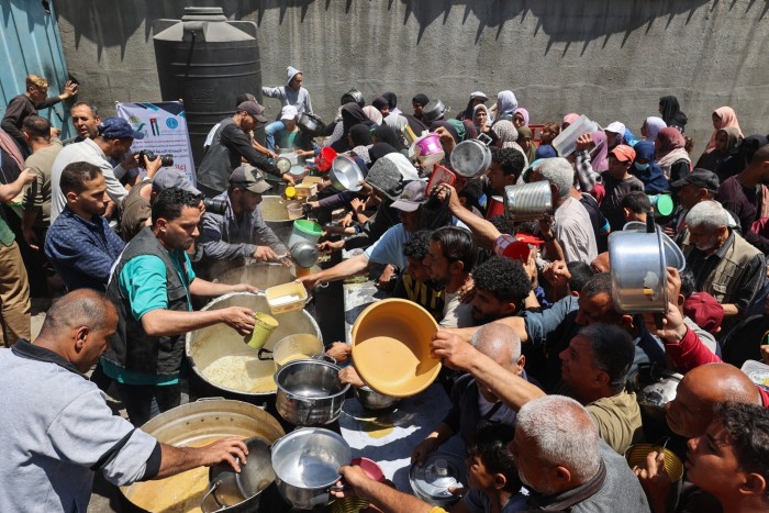 Palestinos cola para una comida caliente en una cocina de caridad dirigida por el Programa de Alimentos Mundiales de la ONU en el Campamento de Refugiados de Nuseirat en el Central Gaza Strip el 26 de abril