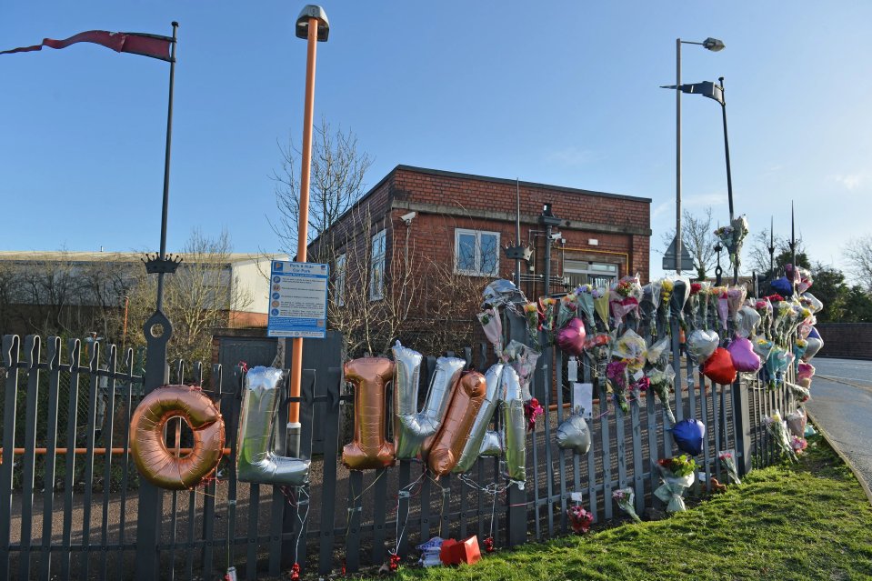 Tributos florales y ortografía de globos "Olivia" adjunto a una cerca cerca de una estación de ferrocarril.