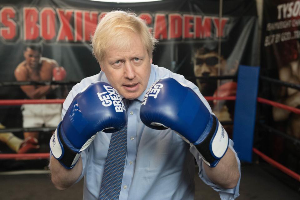 Boris Johnson vistiendo guantes de boxeo que dicen "Hace que Brexit".