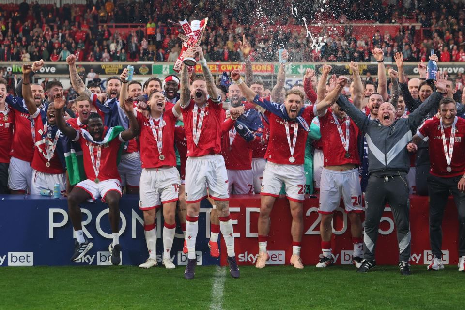 Los jugadores de Wrexham AFC celebran una victoria y levantan un trofeo.